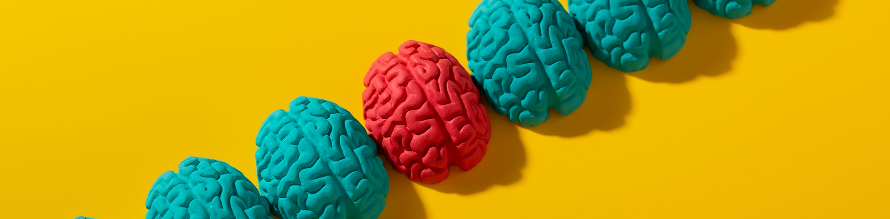 one red brain standing out among blue brains on yellow background illustrating color psychology in logo design